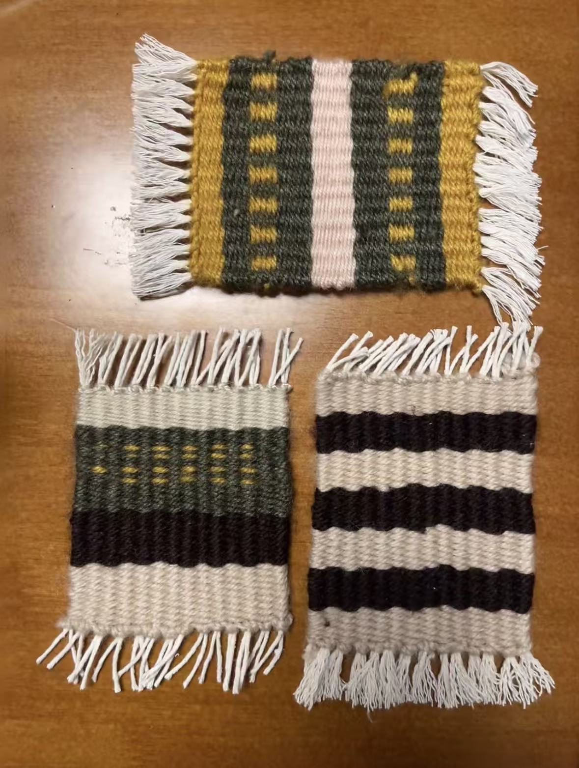 Three finished hand woven coasters on a wooden table