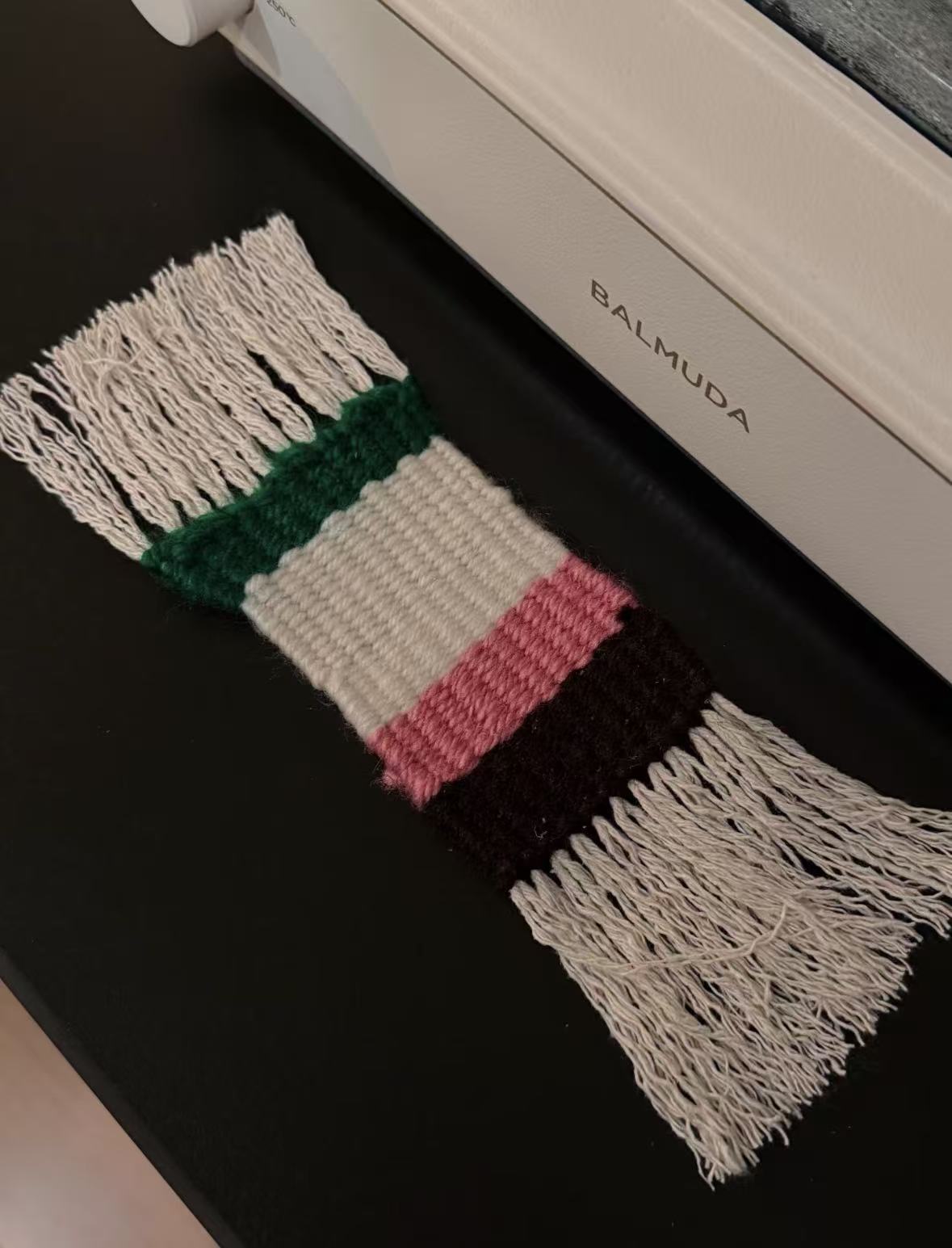 Finished pink, cream, green, and dark brown woven coaster