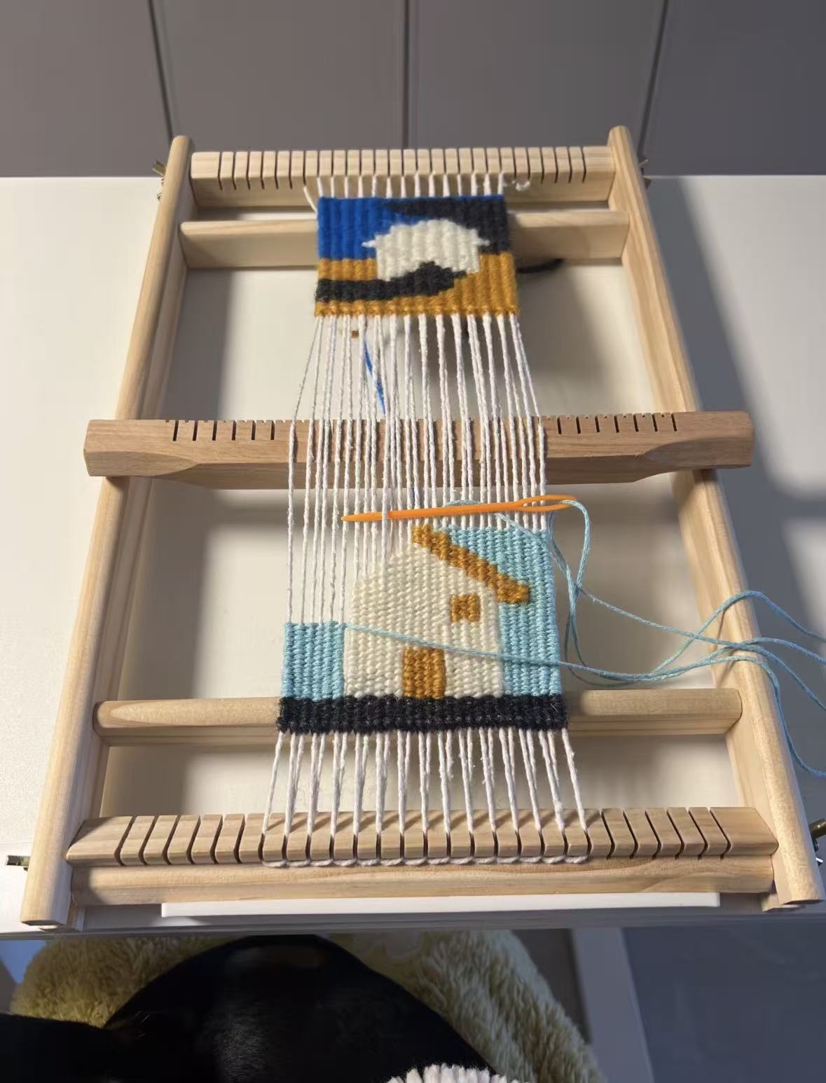 House pattern being woven on a wooden loom